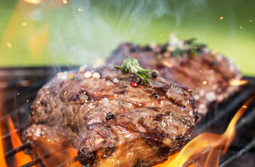 Beef cooking on a flaming grill